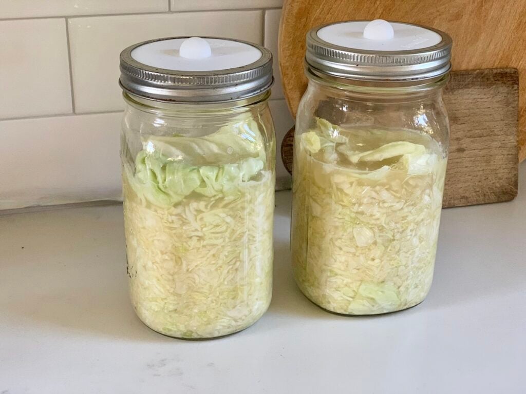 2 mason jars with sauerkraut on kitchen counter