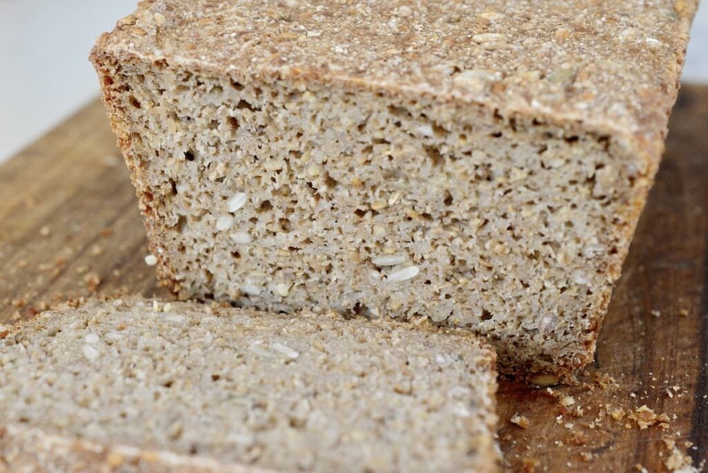 loaf of whole grain bread on cutting board with slices cut