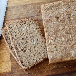 whole grain sourdough loaf with two slices cut on cutting board