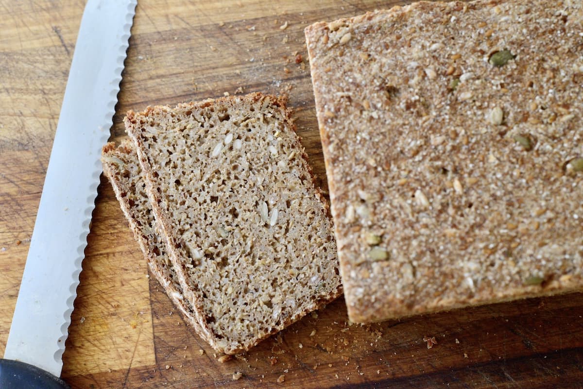 whole grain sourdough loaf with two slices cut on cutting board