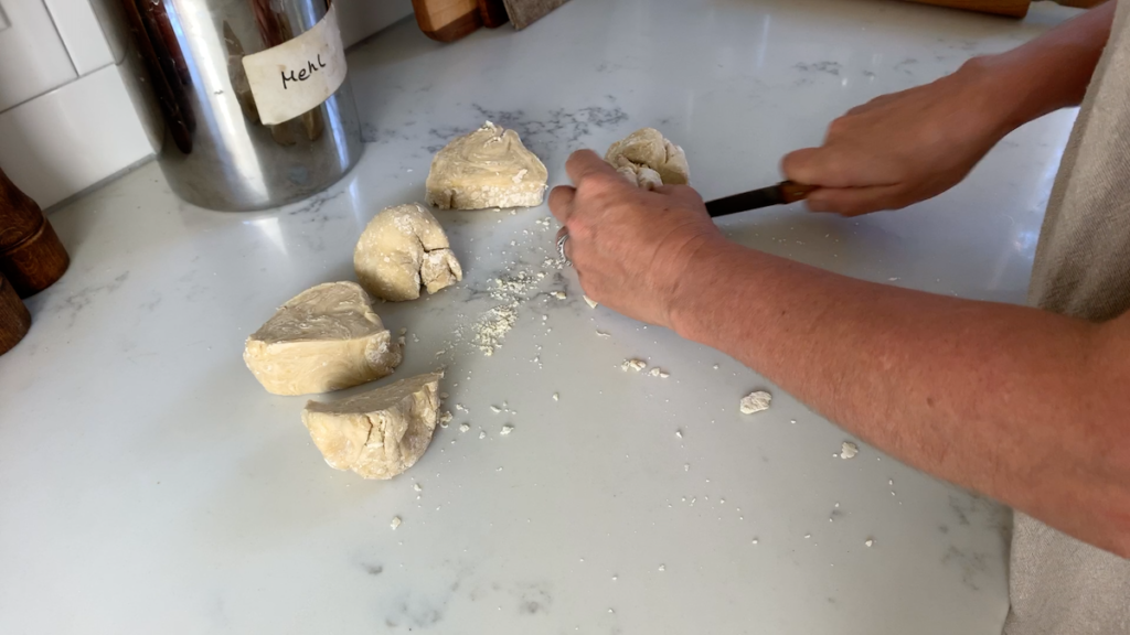 woman cutting pasta dough on kitchen counter