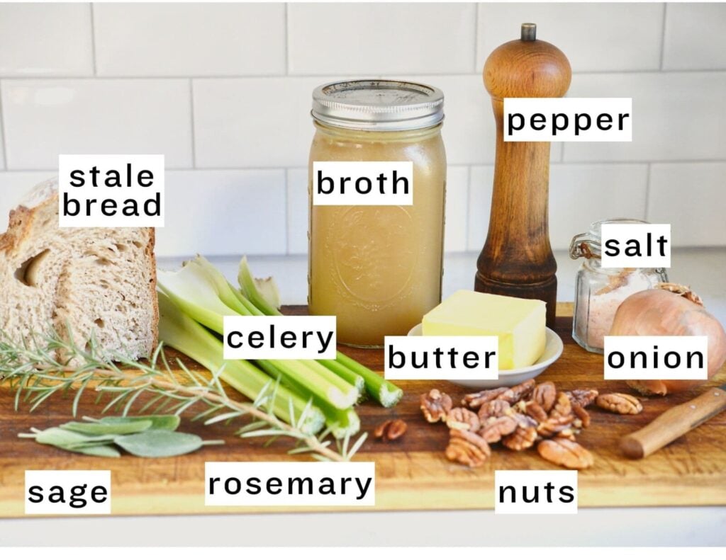 Make-ahead stuffing ingredients: bread, broth, pepper, sage, onion, butter, nuts, sage, and rosemary on cutting board