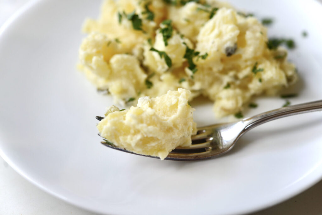 German potato salad on white plate with fork