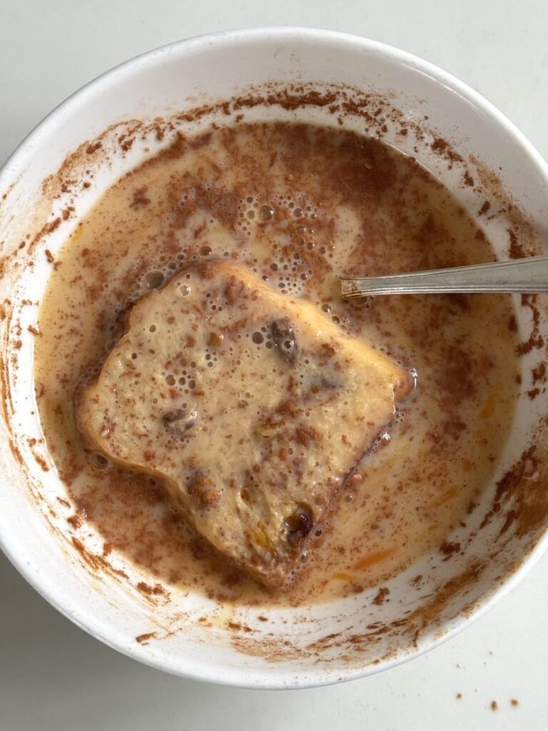 slice of panettone soaking in French toast mixture