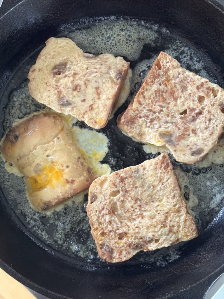 panettone slices with French toast mixture in cast iron skillet