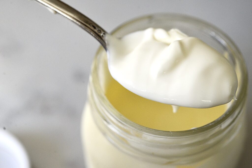 homemade sour cream on a spoon over a mason jar