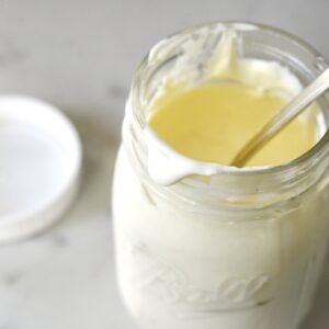 homemade sour cream in a glass jar with spoon