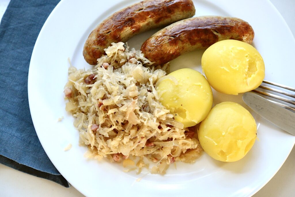 authentic German sauerkraut on a plate with bratwurst and potatoes
