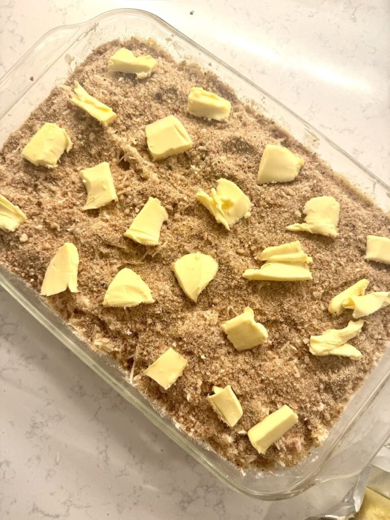 unbaked German ham and noodle casserole with dollops of butter on crust