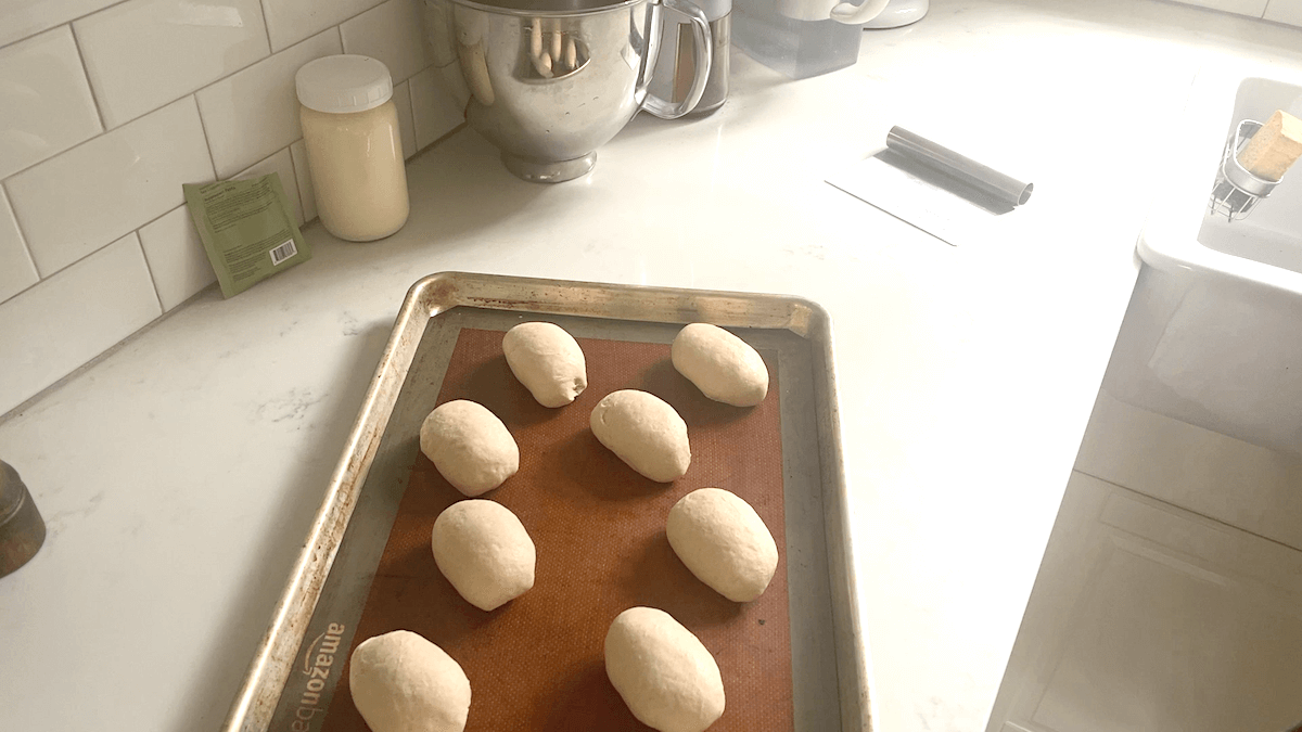 Partially risen brötchen dough on a baking sheet.
