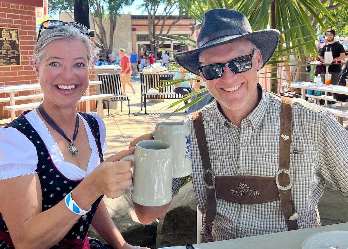 Married couple at Oktoberfest. The woman is wearing a dirndl dress and the man is wearing lederhosen.