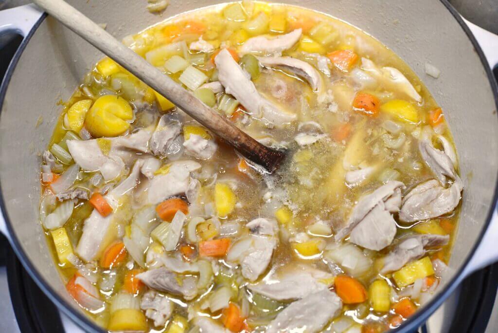 chicken soup in large pot with wooden spoon