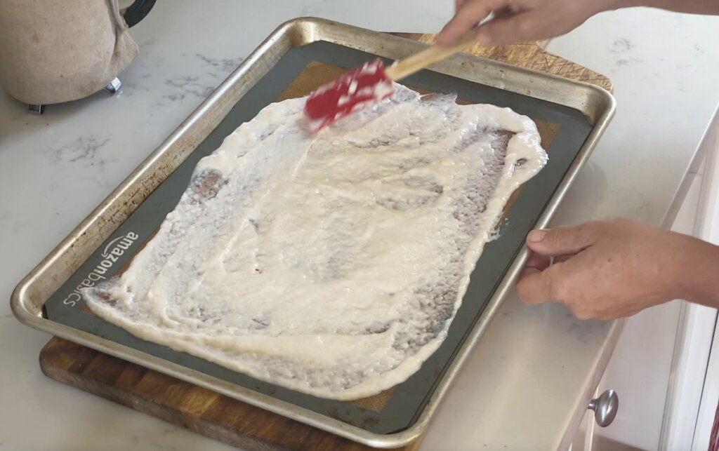 sourdough starter spread with rubber spatula on silicone mat