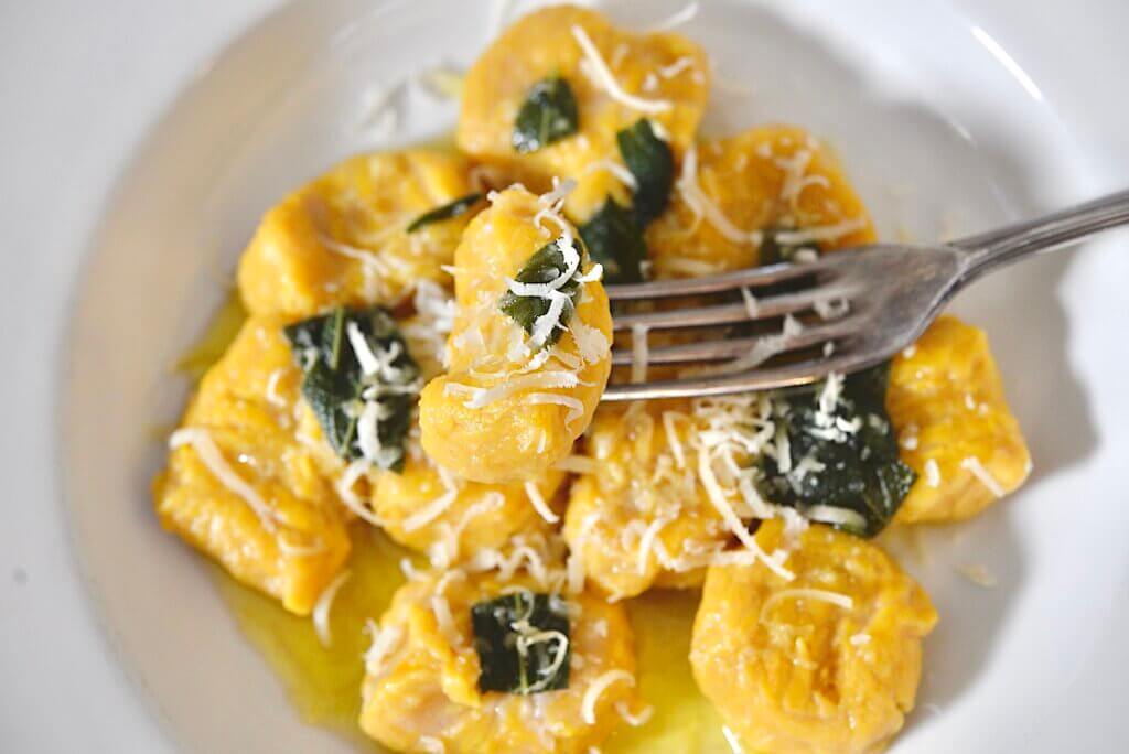 homemade pumpkin gnocchi with sage brown butter sauce on a fork