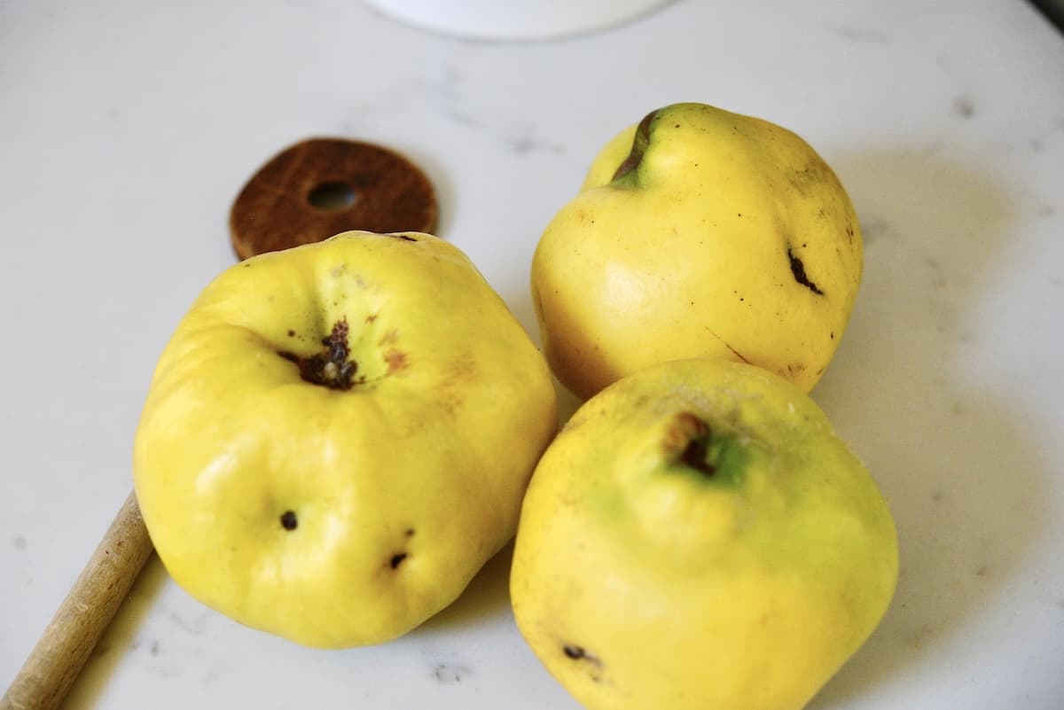 3 quince with wooden spoon on kitchen counter