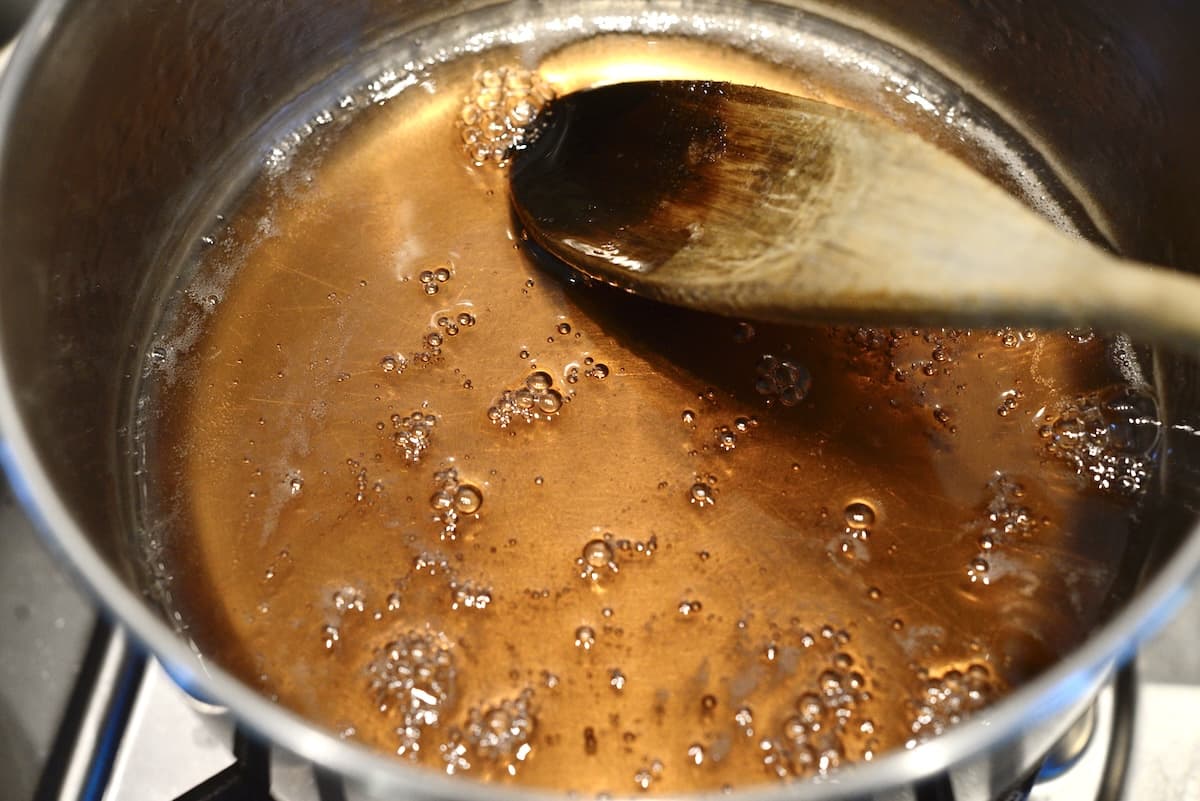 fruit juice cooking and gelling in sauce pot with wooden spoon