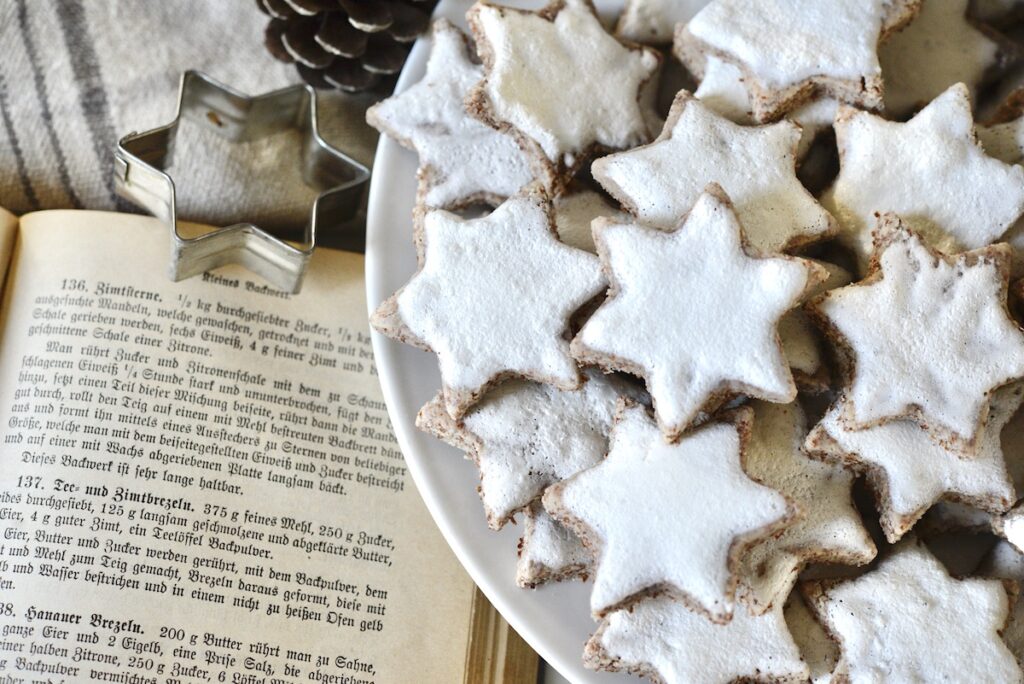 cinnamon star cookies on plate with antique cookbook