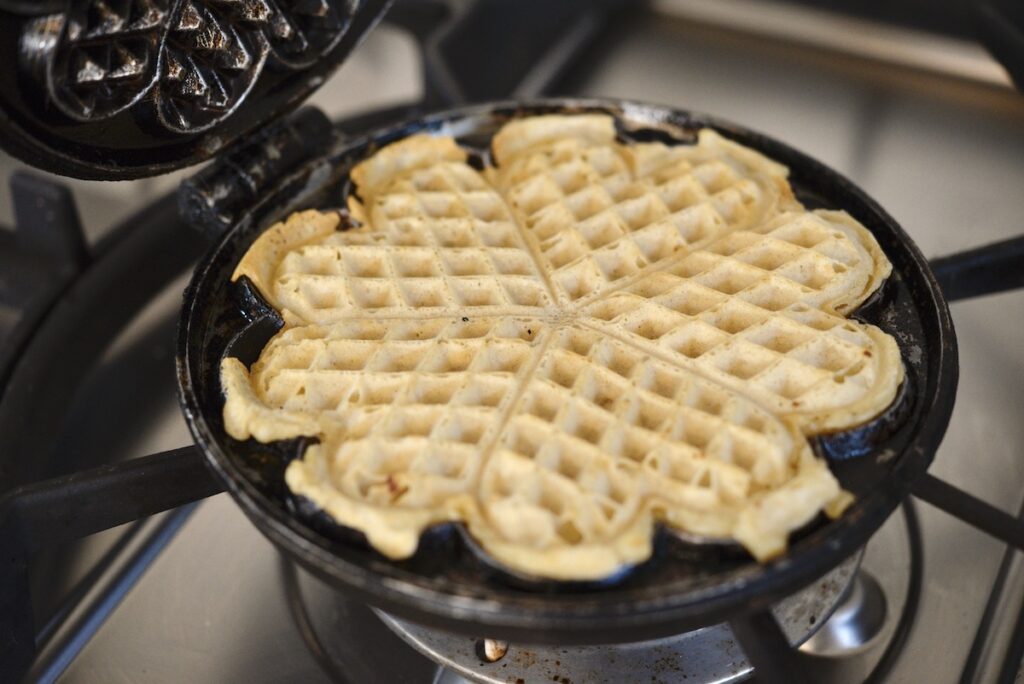 sourdough waffle in cast iron waffle maker on stove top