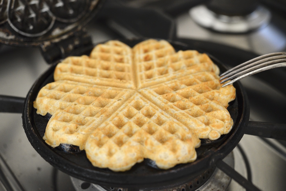 sourdough waffle in cast iron waffle maker on stove