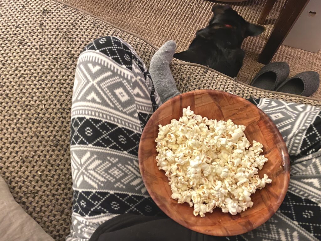 popcorn bowl in lap with a dog in a cozy home