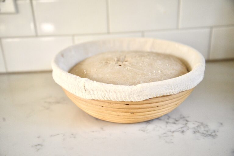 lined rattan bread proofing basket with dough on kitchen counter