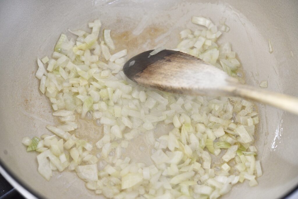 sauteed onion in dutch oven with wooden spoon