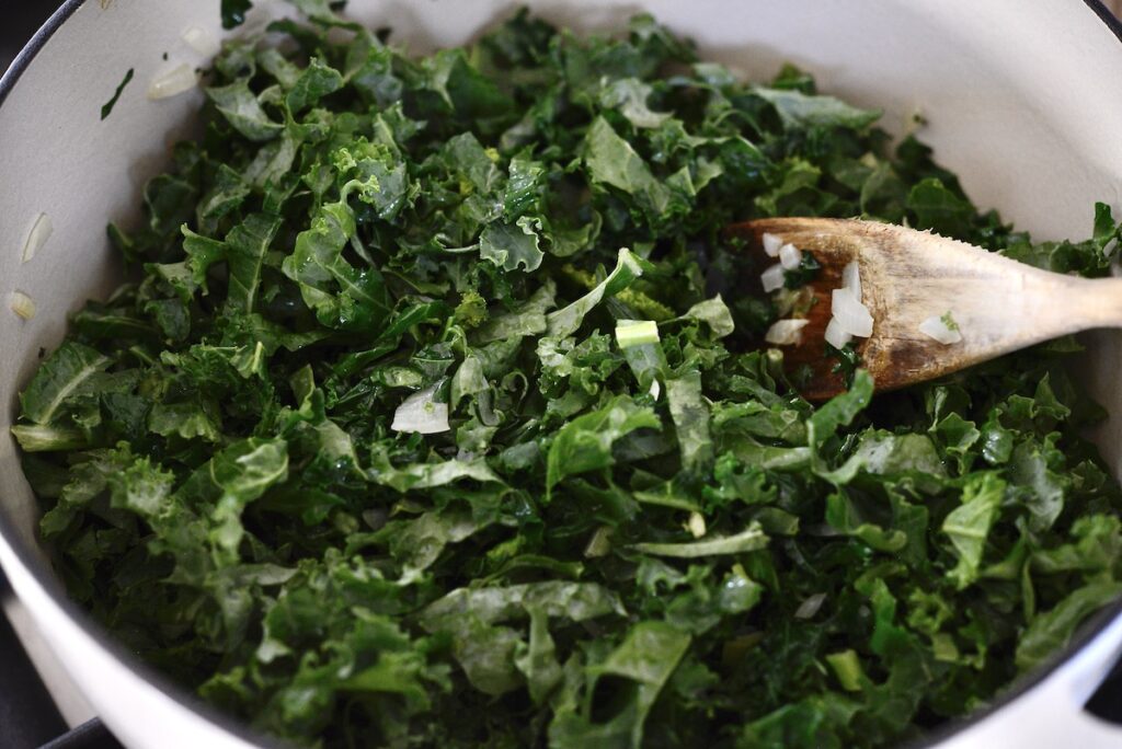 sauteing kale in dutch oven with spoon