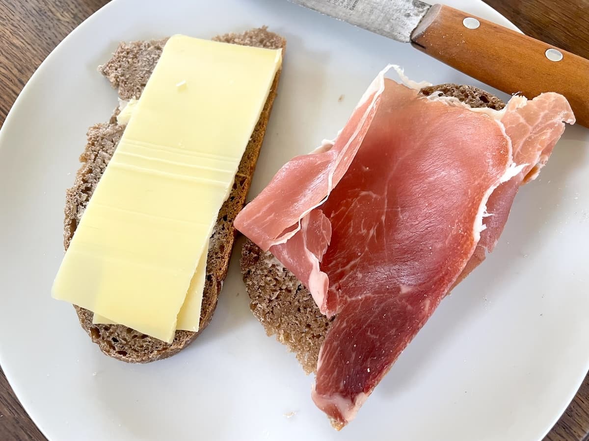 slices of rye bread with cheese and prosciutto