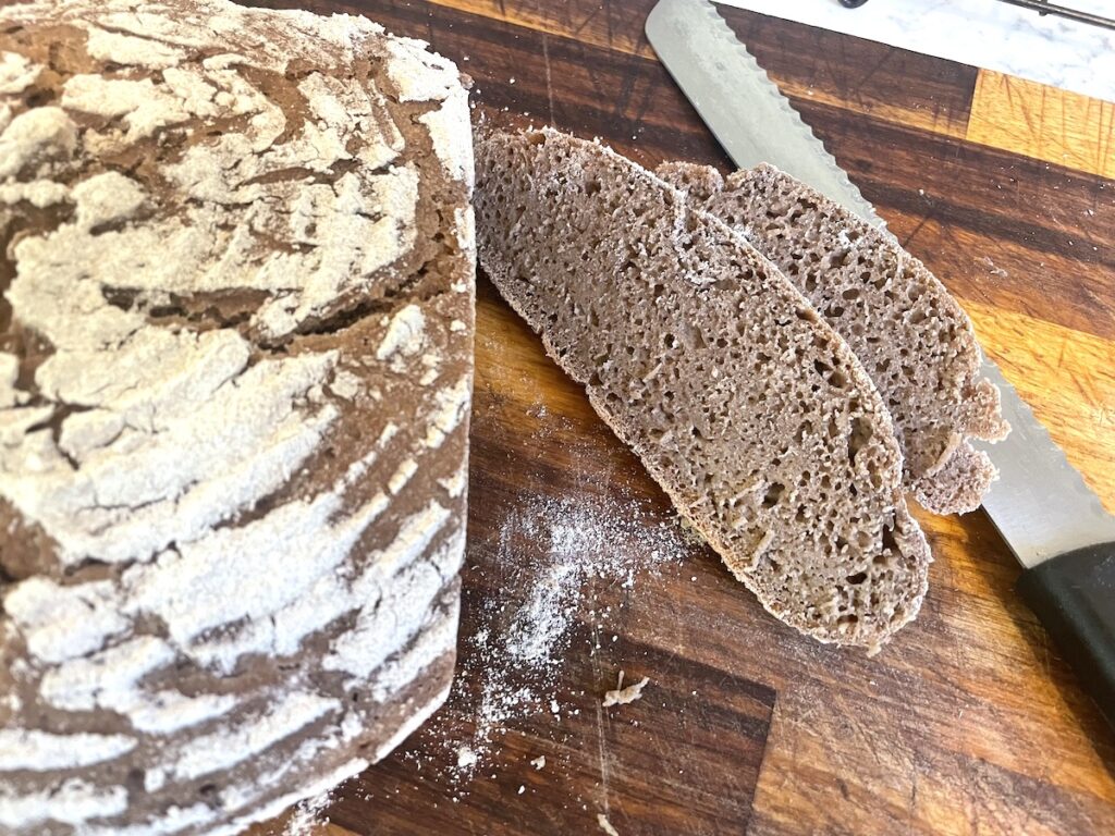 slices and loaf of sourdough rye bread on cutting board with bread knife