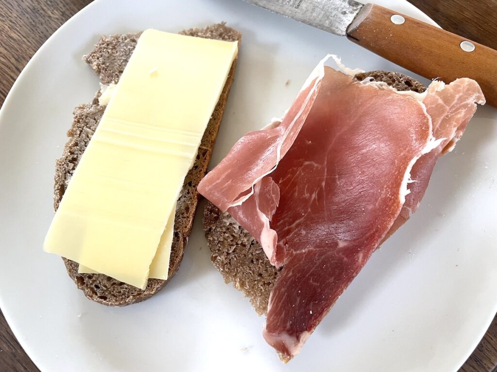 sourdough rye bread slices with cheese and ham on plate