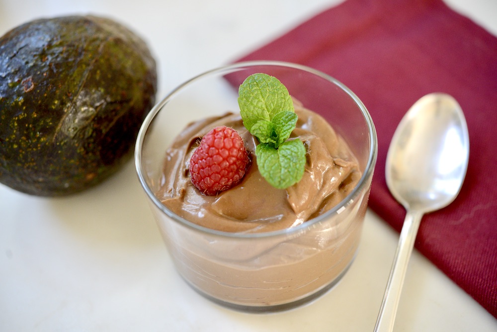 avocado chocolate mousse in glass with avocado, spoon, and napkin