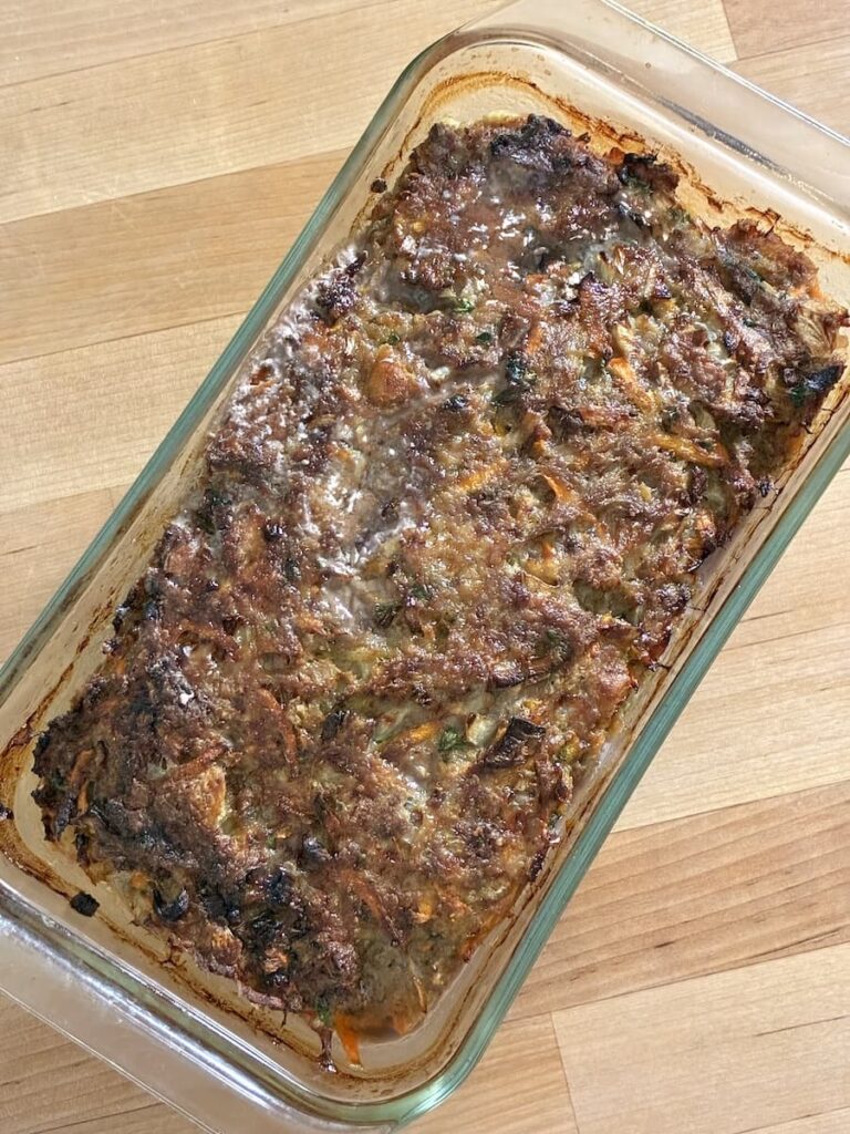 Baked meatloaf in a glass rectangular baking dish on a wooden surface.