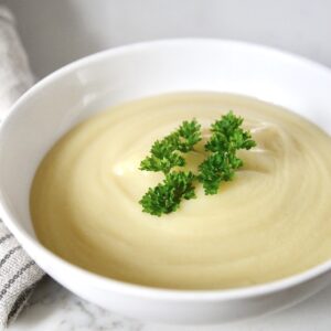 celery soup in bowl with parsley garnish