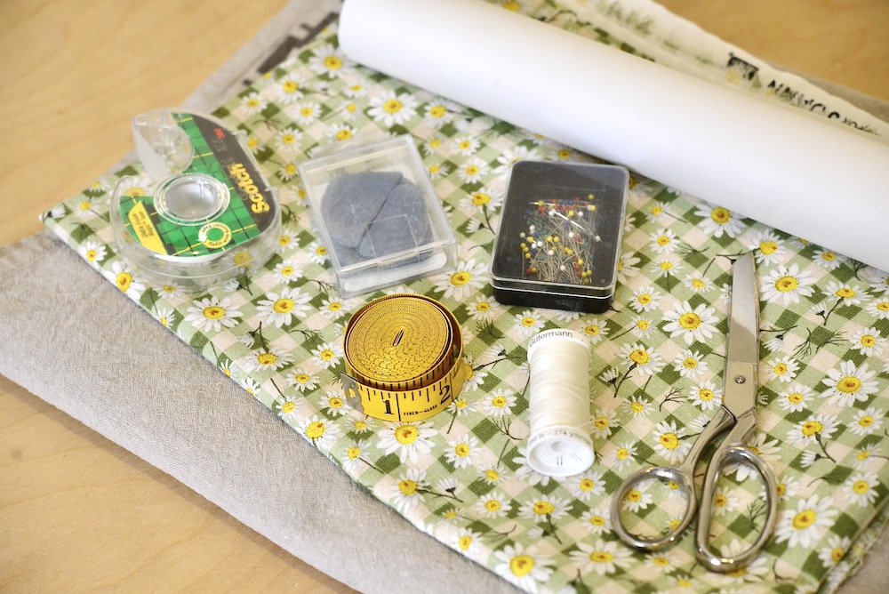 scissors, pattern paper, thread, pins, tailor's chalk, measuring tape, scotch tape, and 2 kinds of fabric