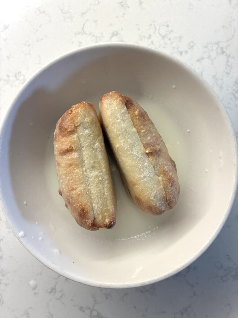 Two pieces of fried dough in a white bowl.