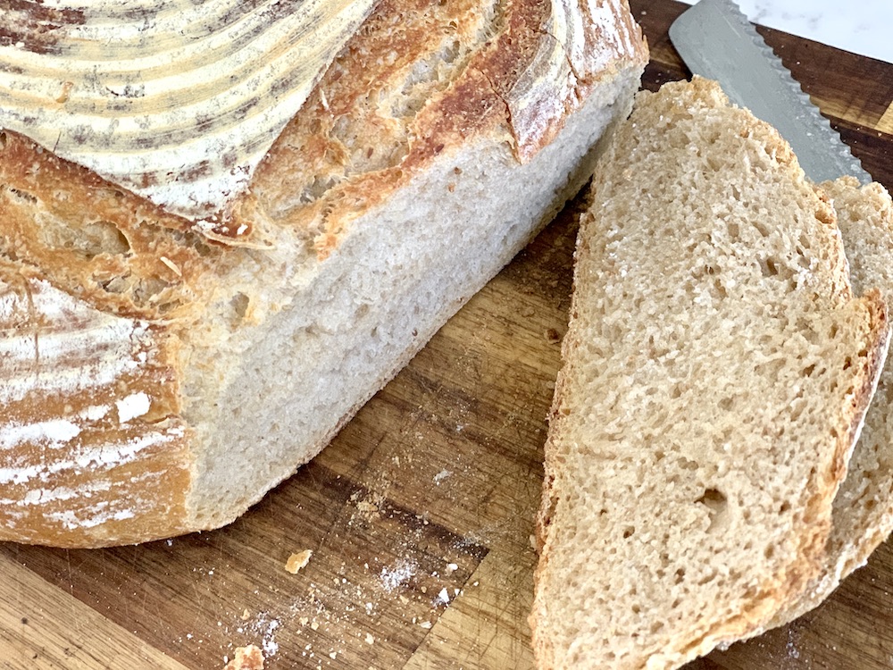 loaf of sourdough bread and slices on cutting board