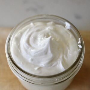 whipped tallow balm in glass jar on wooden board