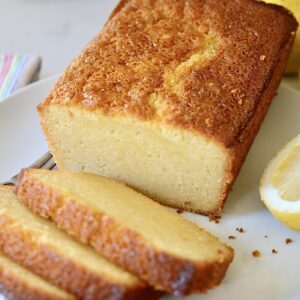 sourdough lemon cake on plate with lemons on the side