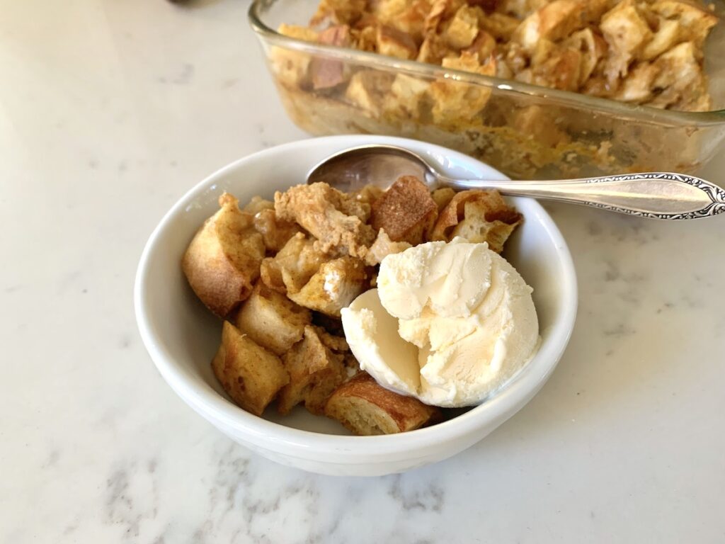 bread pudding in bowl with ice cream and spoon