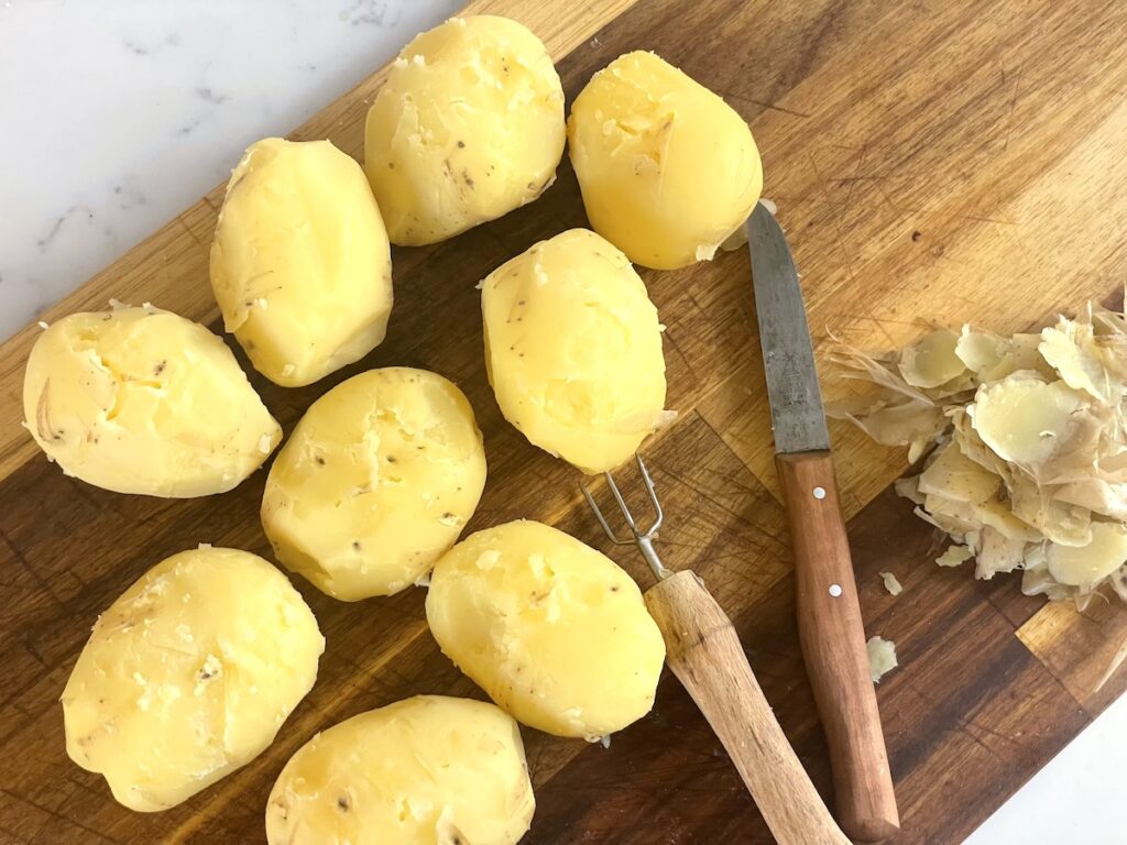 peeled potatoes on cutting board with knife and potato pick