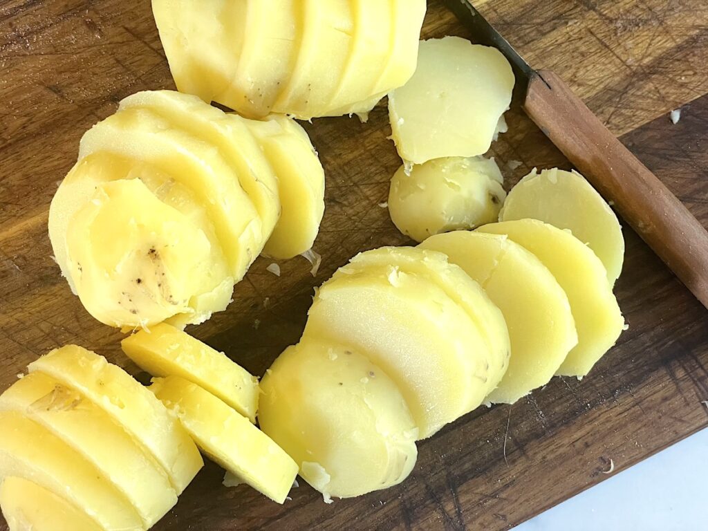 sliced potatoes on cutting board with knife