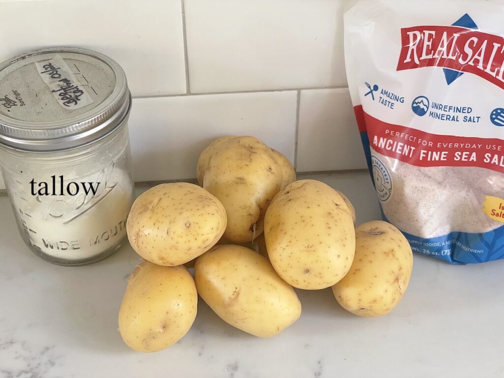 tallow in mason jar, golden potatoes, and sea salt on kitchen counter