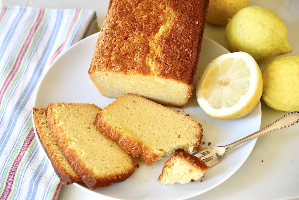 sourdough lemon cake on plate with fork and lemons on the side