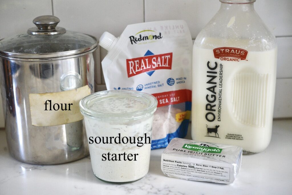 flour, sourdough starter, salt, milk, and butter on kitchen counter