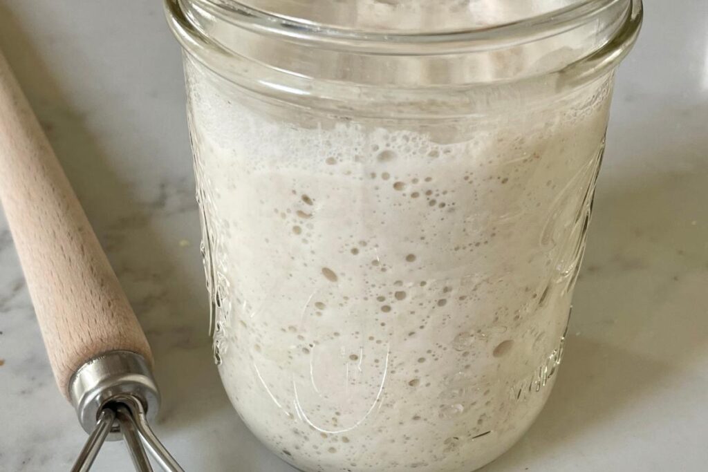 active sourdough starter in glass jar with Danish dough hook
