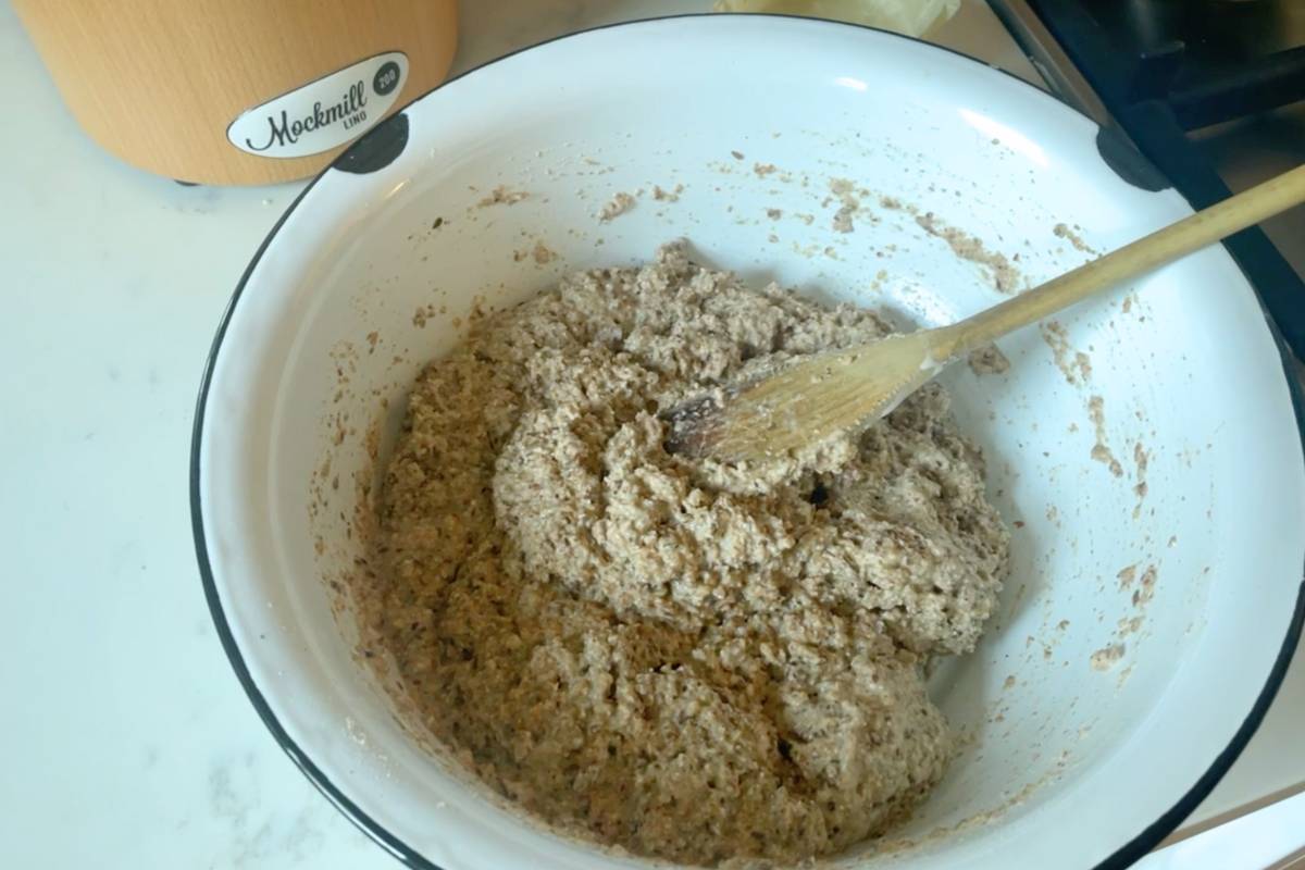Whole grain sourdough bread dough in a large white  mixing bowl.