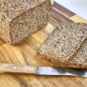 whole grain sourdough bread with slices with knife on cutting board