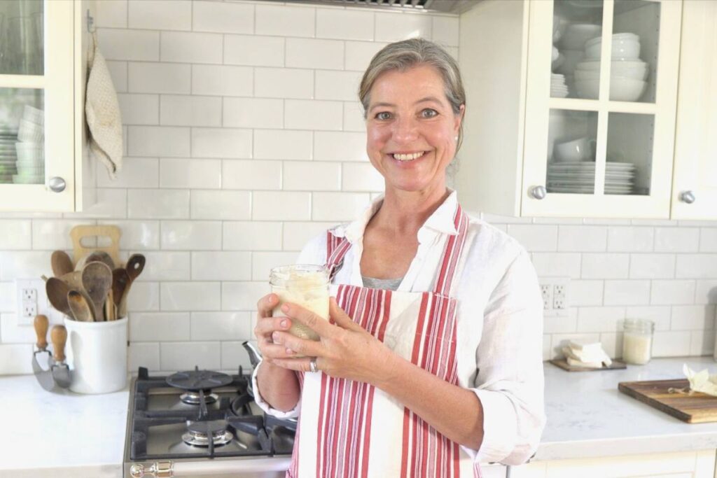 Anja Eckert in her kitchen with a jar of sourdough starter in her hand