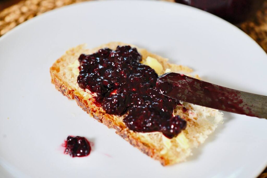slice of German bread with homemade jam with knife on white plate