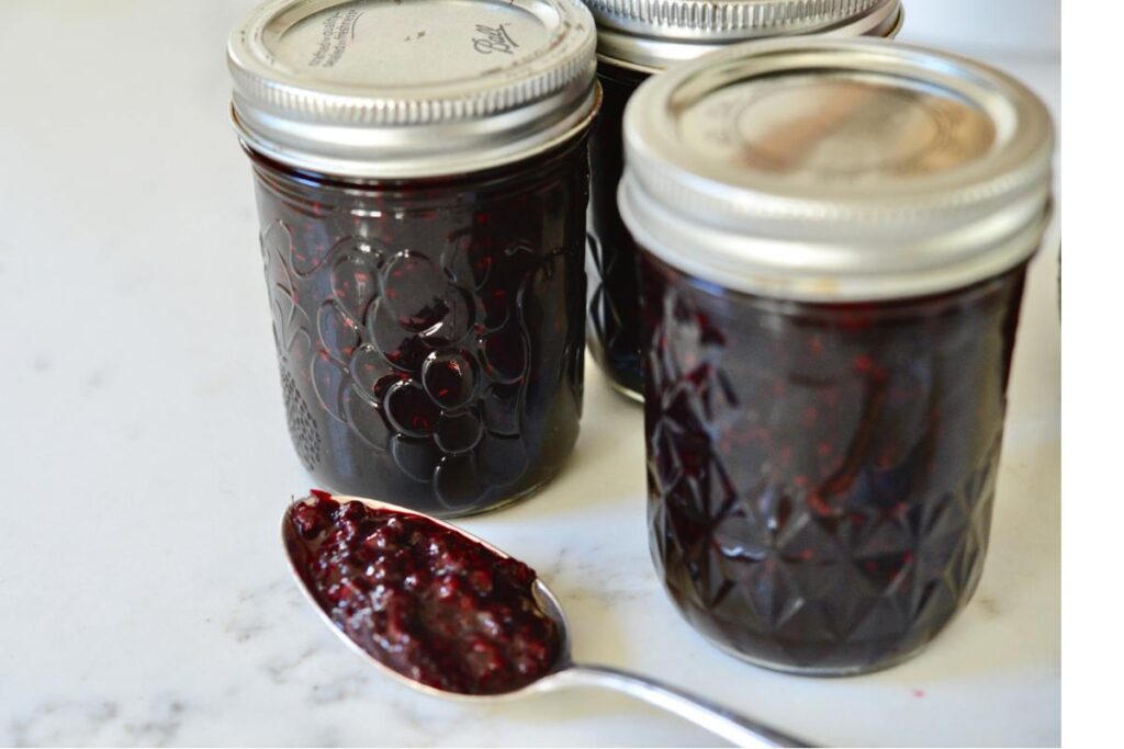 3 jars of elderberry jam with a spoon 